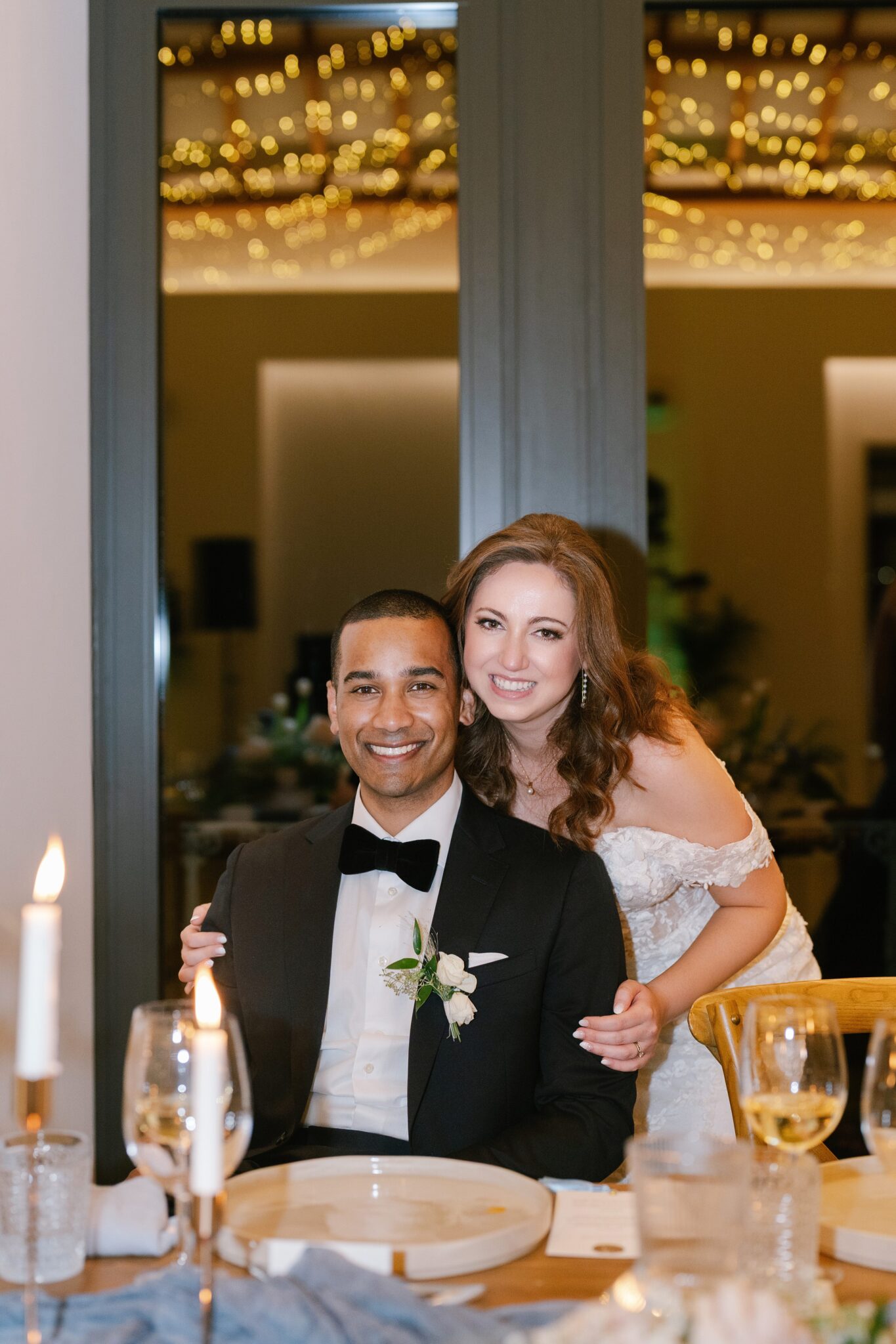 Bride and groom smiling at their reception table at Quinta do Gradil with fairy lights in the background