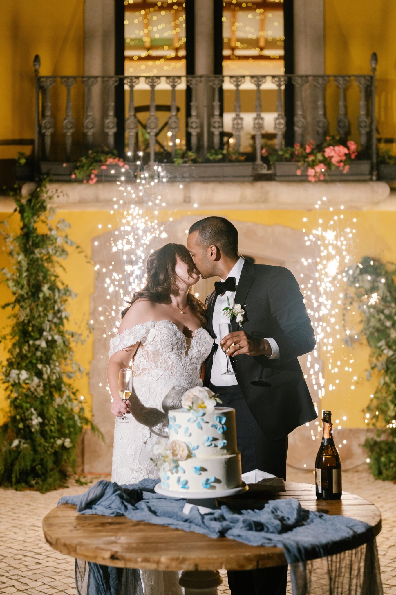 Bride and groom kissing in front of wedding cake with sparkling fireworks at Portugal villa Quinta do Gradil
