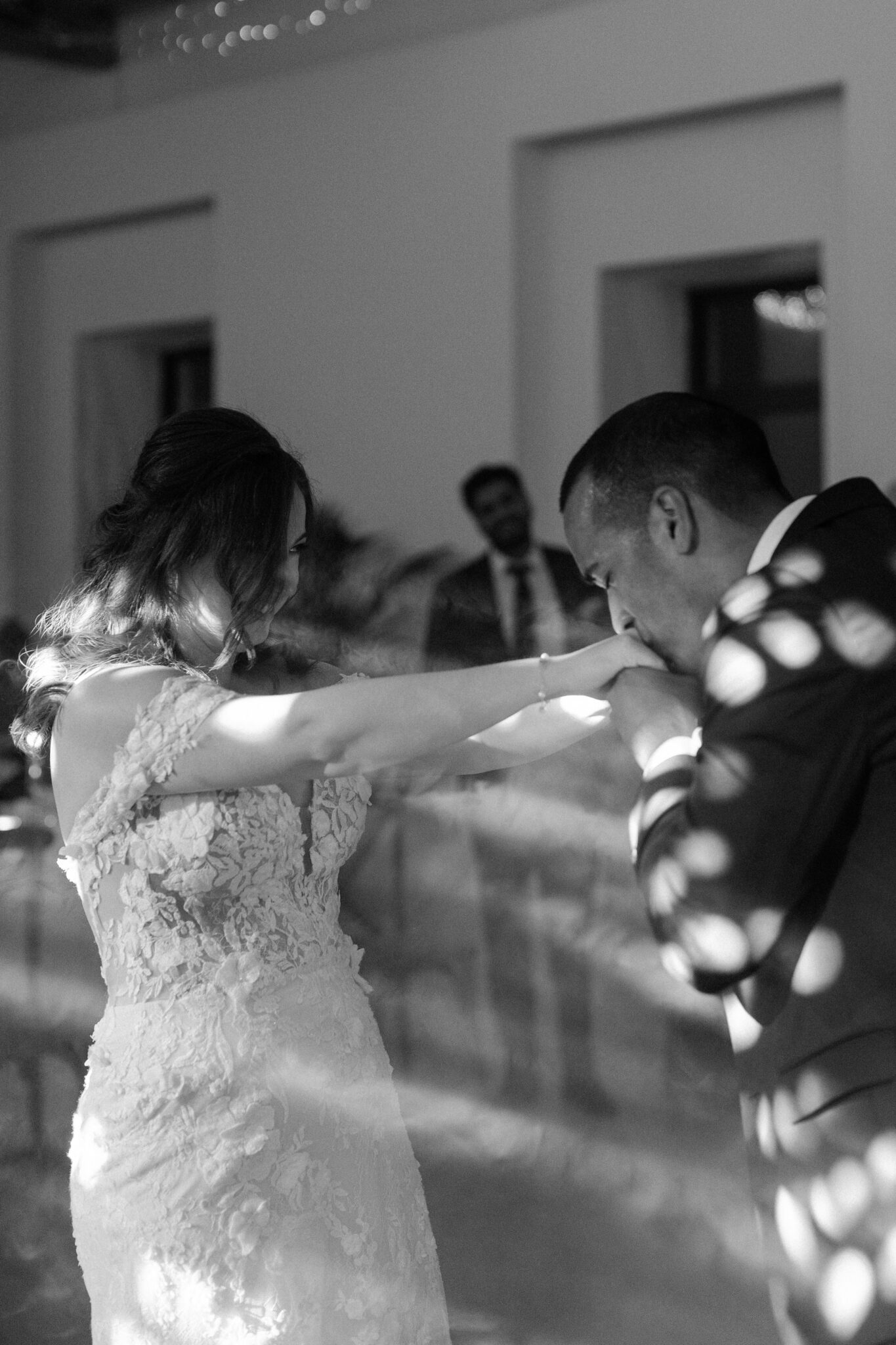 Groom kissing bride’s hand during first dance black and white photo in Portugal