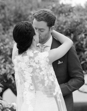 Bride and groom sharing a tender kiss during their First Look in a black and white photograph.